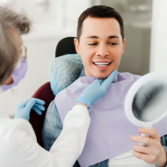 Man smiling at reflection in mirror with dentist