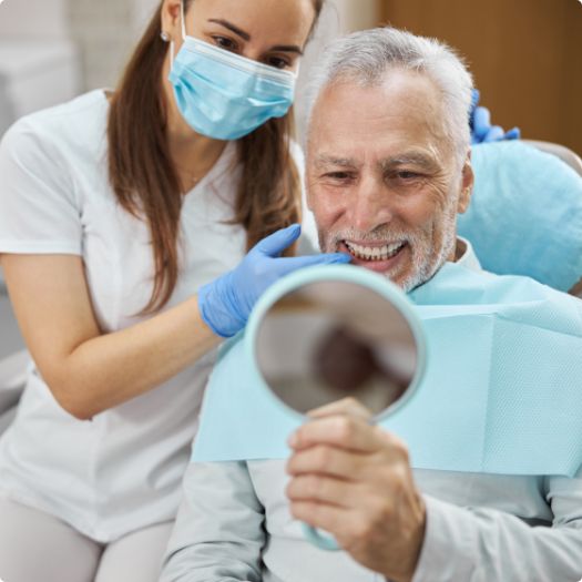 Senior dental patient admiring his smile in mirror