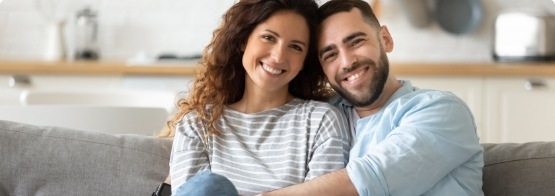 Man and woman smiling on couch after receiving dental services in Cinco Ranch