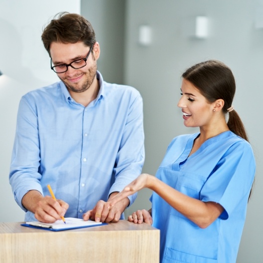 Dental team member showing a patient where to sign on form