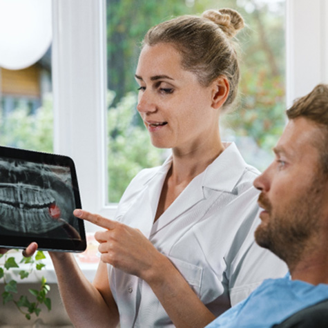 Dentist showing patient his X-rays with red wisdom teeth