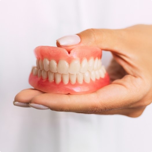 Hand holding a set of full dentures