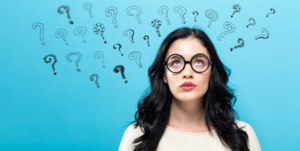 Woman looking up at several question marks floating above her head