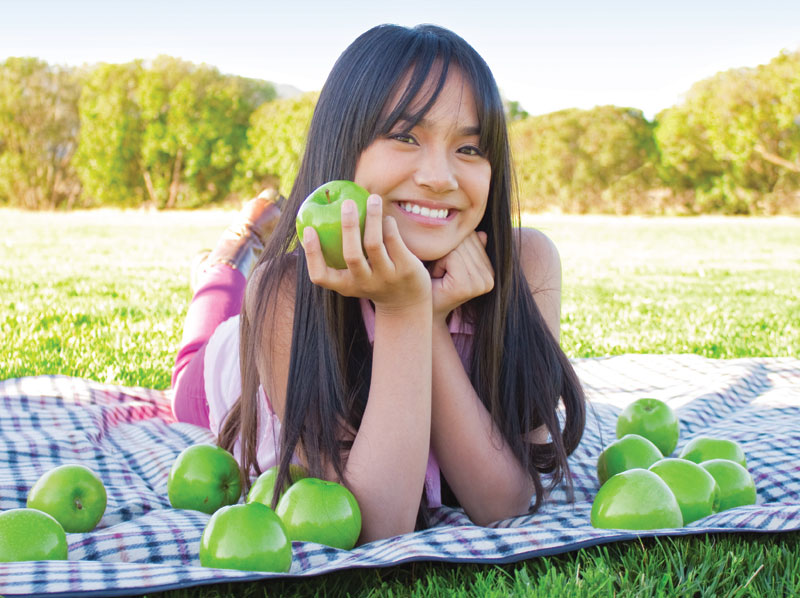 Young lady smiling with apples.